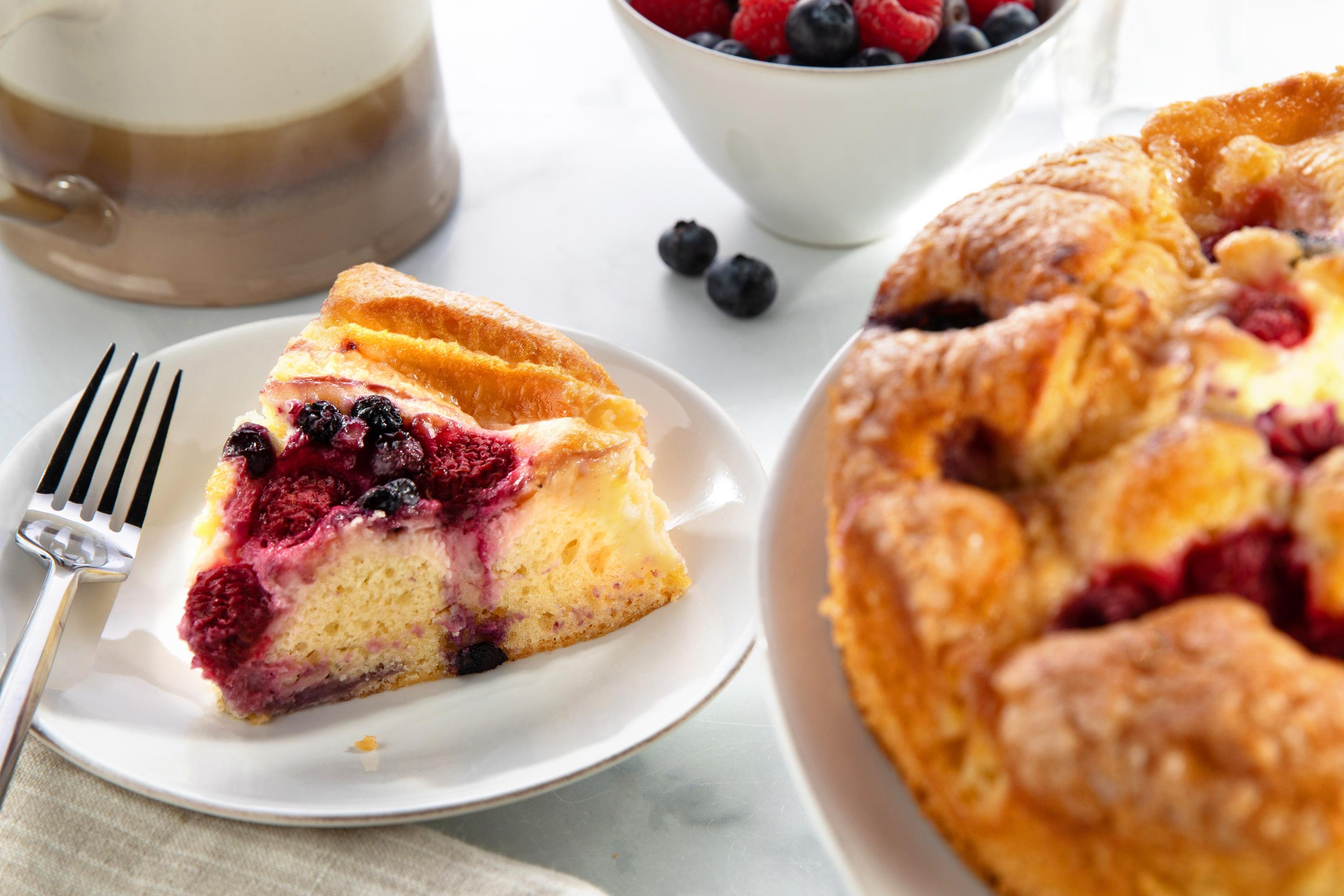 Close-up of DLM lemon berry coffee cake topped with fresh berries and a golden crumb
