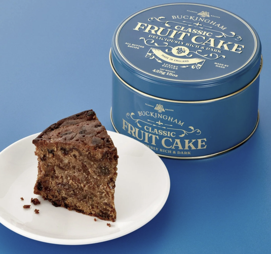 Buckingham Classic Fruit Cake sliced o white plate and shown packaged in a luxury blue tin