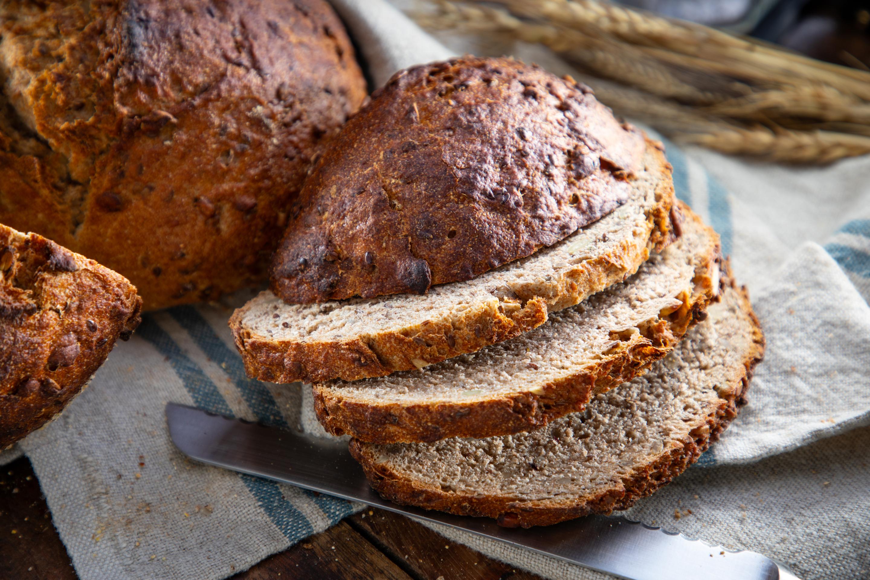 Sliced 100% Spelt Bread with Seeds from Dorothy Lane Market showing open, chewy crumb with visible pumpkin and sunflower seeds
