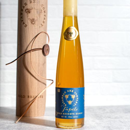 Savannah Bee Company Tupelo Gold Reserve Honey in a tall glass flute, golden-green honey from white tupelo blossoms