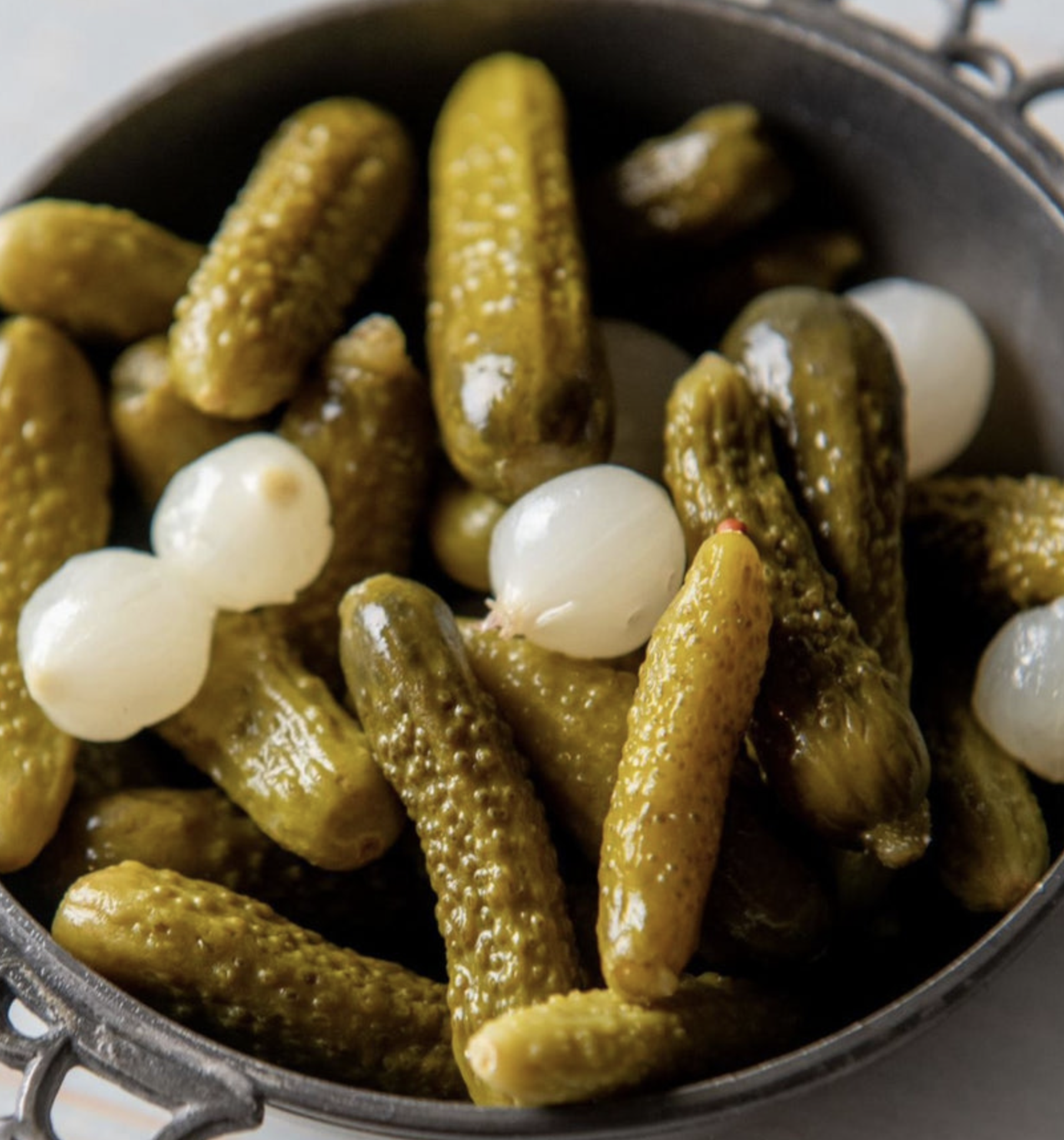 Cornichons served as a side with pâté and rustic bread on a wooden board